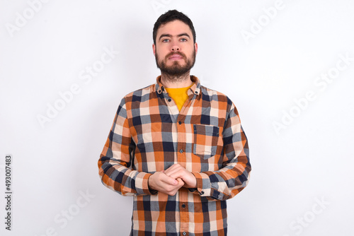 Photo of cheerful confident young caucasian man wearing plaid shirt over white background arms together