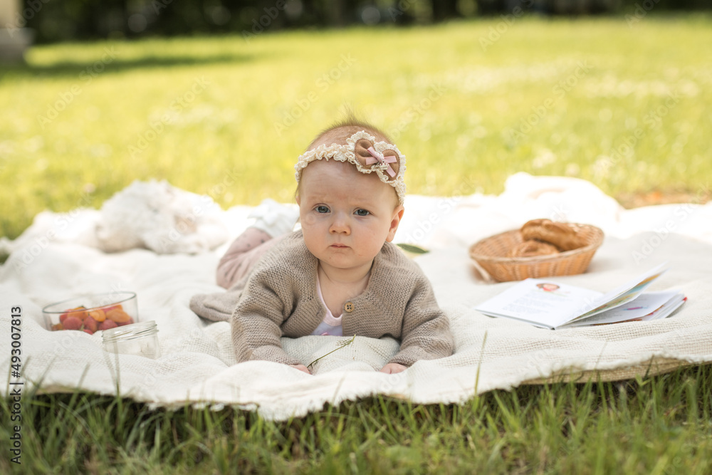 little girl lies on a blanket at a summer picnic