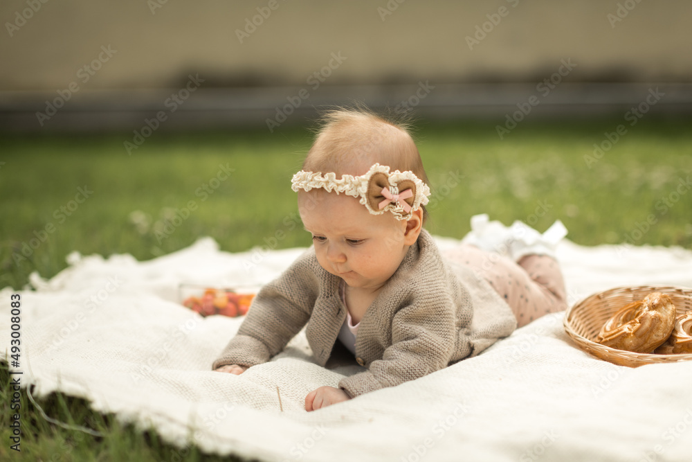 baby girl lies on a plaid, summer picnic for children