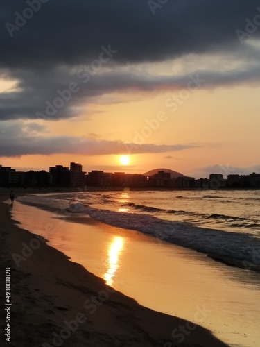 Sunset on the beach with the golden sun reflected in the wet sand.
