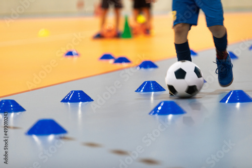 Boy in Soccer Clothes with Futsal Ball on Dribbling Drill. Kid on Indoor Soccer Training With Coach. Child Playing Futsal on Wooden Floor. Futsal School Practice With Coach Trainer