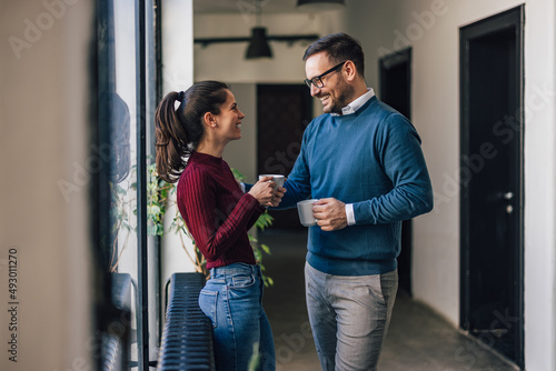 Two colleagues taking a break from work, drinking coffee, talkin photo