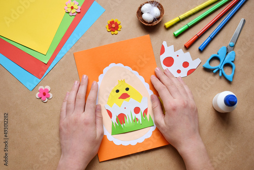 Making of handmade Easter decoration. Child made greeting card in egg shape. Childrens DIY concept, gift with your own hands. Hobby, paper crafts at home or  in kindergarten.