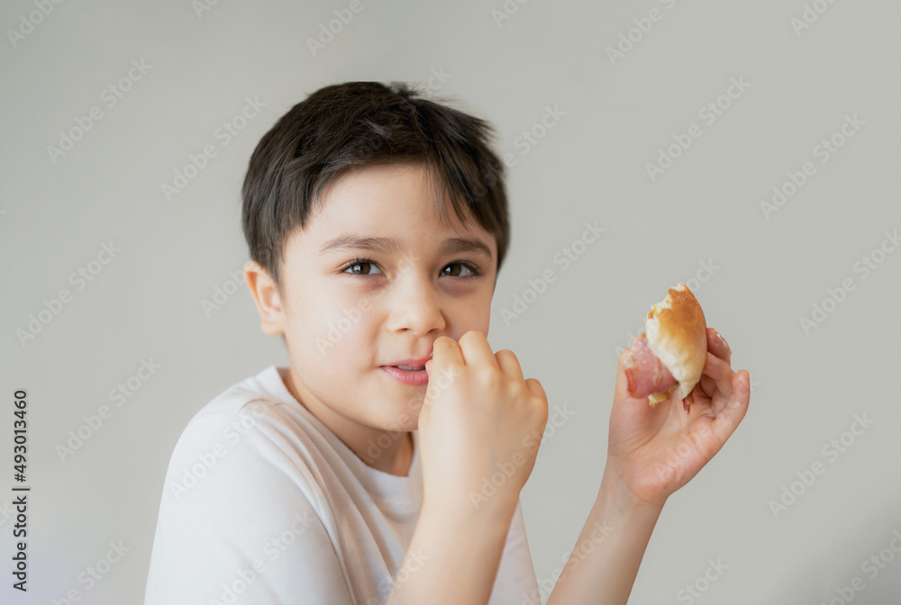 Hungry young boy eating homemade bacon sandwiches with mixed vegetables, Healthy Kid having breakfast at home, Child bitting finger nails and looking out with thinking face Hungry young boy eating homemade bacon sandwiches with mixed vegetables, Healthy Kid having breakfast at home, Child bitting finger nails and looking out with thinking face
