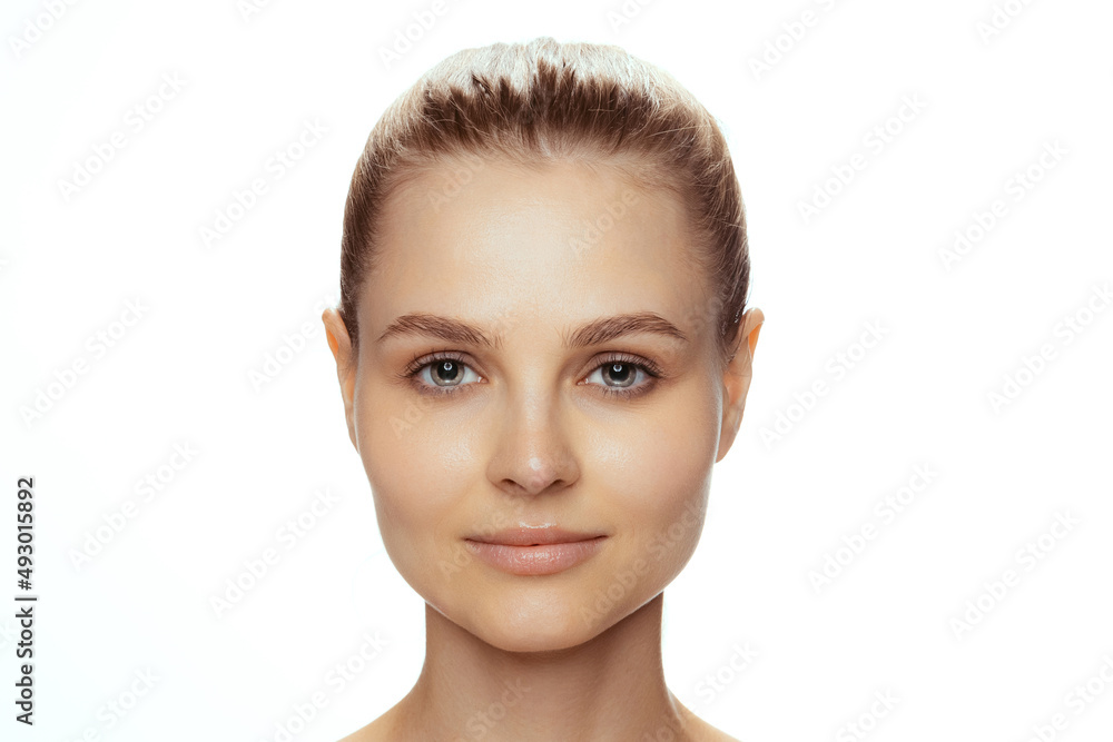 Portrait of young beautiful woman with perfect no makeup face, looking at camera isolated over white studio background Portrait of young beautiful woman with perfect no makeup face, looking at camera isolated over white studio background