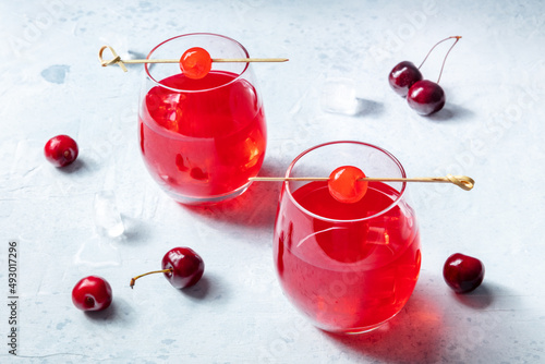 Cocktail with cherry and ice, an aperitif with a garnish and fresh berries, cold summer drink