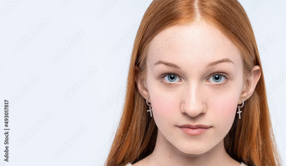 Obraz premium Close up portrait of Red-haired teenage girl looking at camera. Cute teenage girl woman face closeup portrait with healthy clean skin isolated on white background. Copy space.