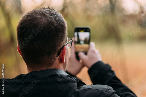 Mann mit Brille fotografiert mit seinem Smartphone horizontal