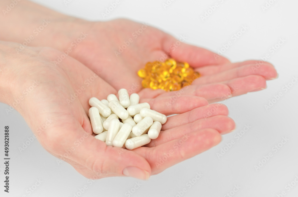 White capsule pills in female hands, selective focus White capsule pills in female hands, selective focus