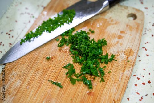 A dollop of chopped chives chopped with a knife on a cutting board