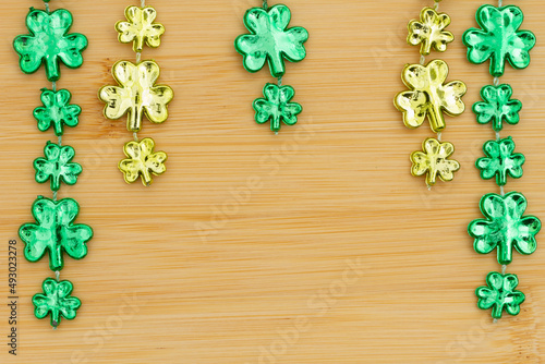 Green shamrocks on light brown grained wood background