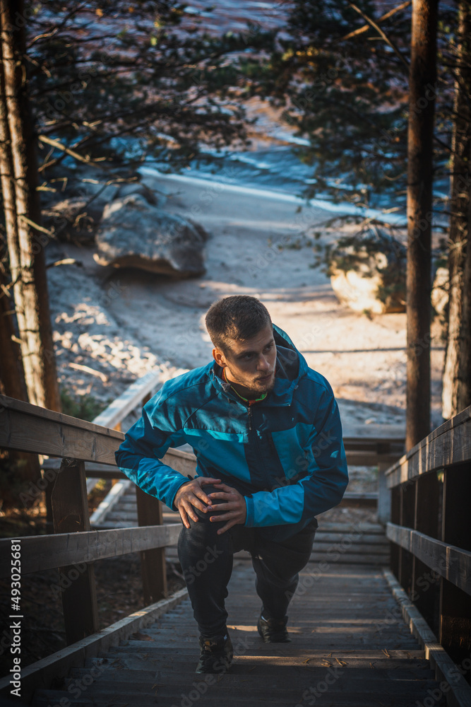athlete in his training runs up the stairs for better fitness. A 20-year-old athlete in a blue jacket in summer training. Sotkamo, Finland. Active lifestyle athlete in his training runs up the stairs for better fitness. A 20-year-old athlete in a blue jacket in summer training. Sotkamo, Finland. Active lifestyle