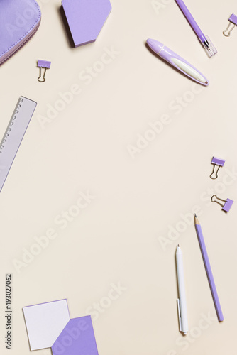 School stationery flat lay very peri trend color. Back to school concept, notebook, note, pen, pencil, pencil case, paper clips on pastel beige background. Office equipment, top view