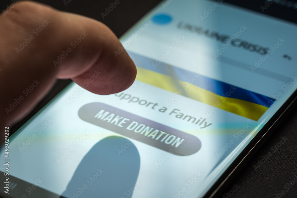 Naklejka premium Close-up finger pressing make donation button on smartphone screen. Donation money online concept
