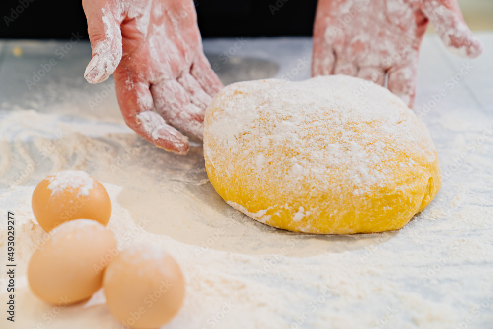 women's hands with dough, flour and eggs on table women's hands with dough, flour and eggs on table