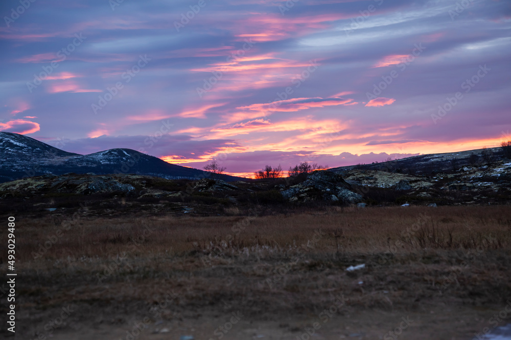 Autumn dawn scenery in the Dovrefjell, Norway, with rocks, hills, mountains, and patches of snow