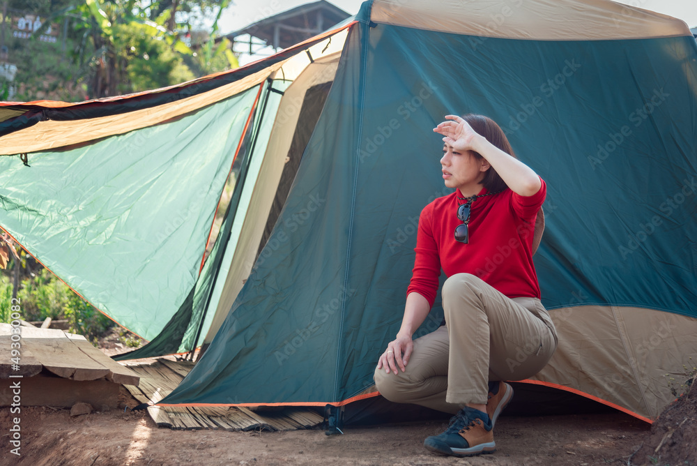 An Asian woman is tired while pitching a tent at Hadubi viewpoint, Chiang Mai, Thailand.