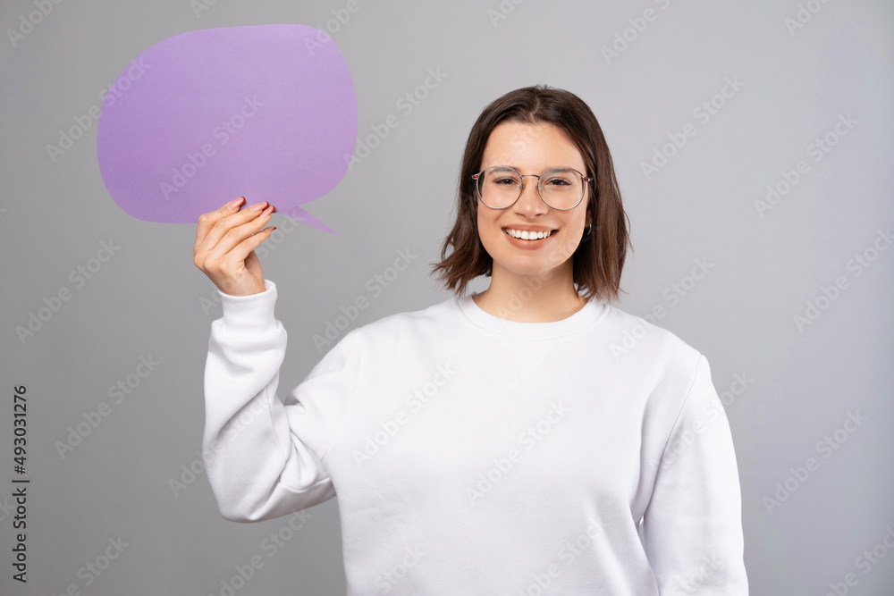 Content young woman with short hair is holding a purple speech bubble. Content young woman with short hair is holding a purple speech bubble.