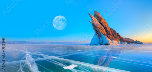 Fototapeta Naklejka Na Ścianę i Meble -  Ogoy island on winter Baikal lake with transparent cracked blue ice with full moon at sunrise - Baikal, Siberia, Russia 