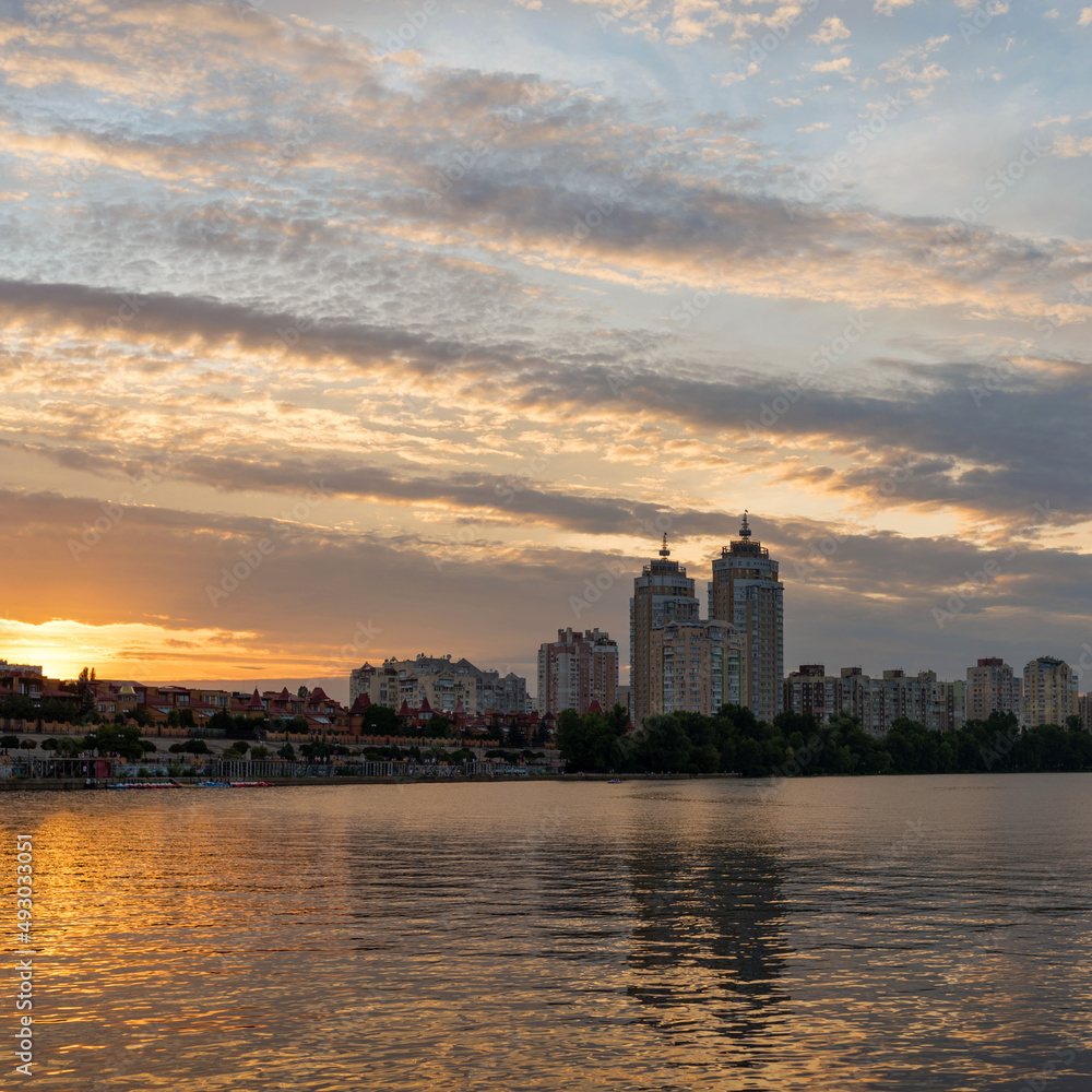 Embankment on Obolon in Kyiv. Summer landscape with reflection of the colorful evening sky in the Dnipro
