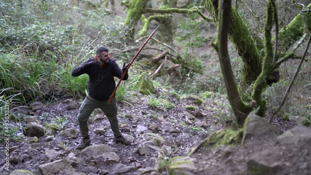 Toma 4k de chico realizando senderismo con un palo de ayuda 