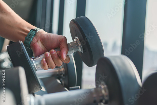 Athlete in the gym training with dumbbells.,Man is engaged with dumbbells on the bench. Hands with dumbbells