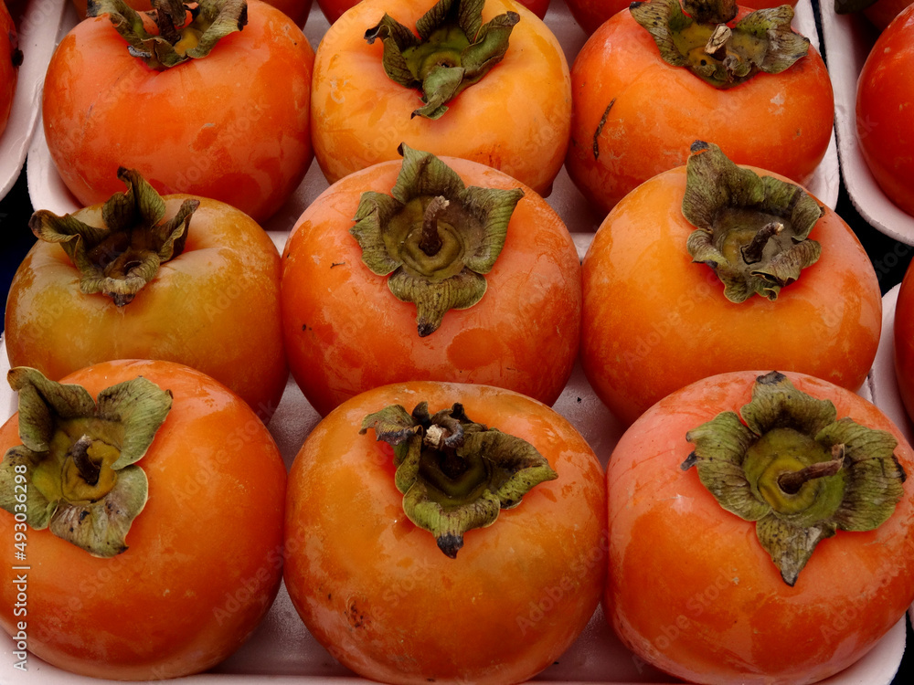 Persimmon fruits on a farmers market stall in the Aegean coastal town Yalikavak, Bodrum, Turkey. Persimmon fruits on a farmers market stall in the Aegean coastal town Yalikavak, Bodrum, Turkey.