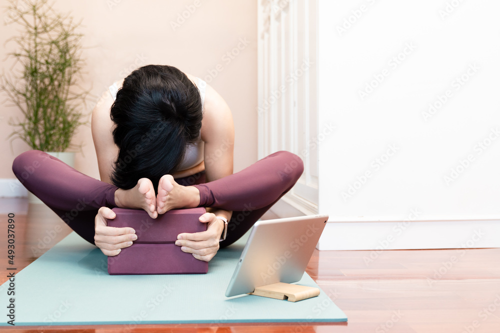 A healthy asian female using yoga blocks to warm up and stretching her