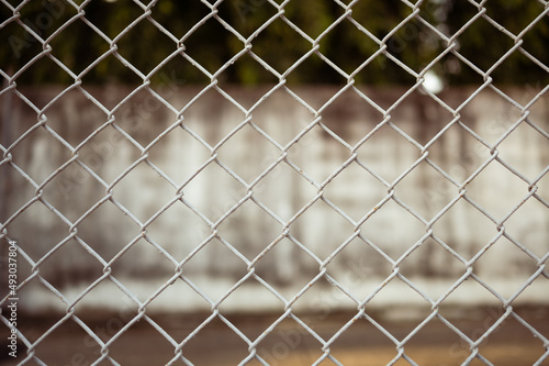 The image of a white barbed wire fence and a wall is used for the background illustration.