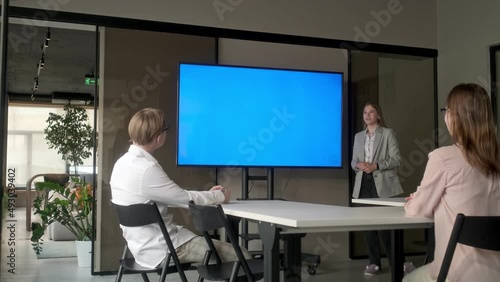 Diverse office conference room meeting: female project manager uses Chroma Key wall mounted blue screen TV to present an investment project. Project presentation. Business concept, training