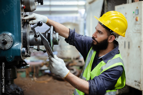 Man engineer wear yellow helmet holding tablet and uniform working at industrial workshop. handsome workman with beard on face ​in factory. Copy space.