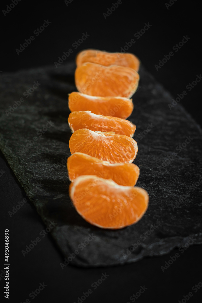 Tangerine segments on black stone tray. Tangerine segments on black stone tray.