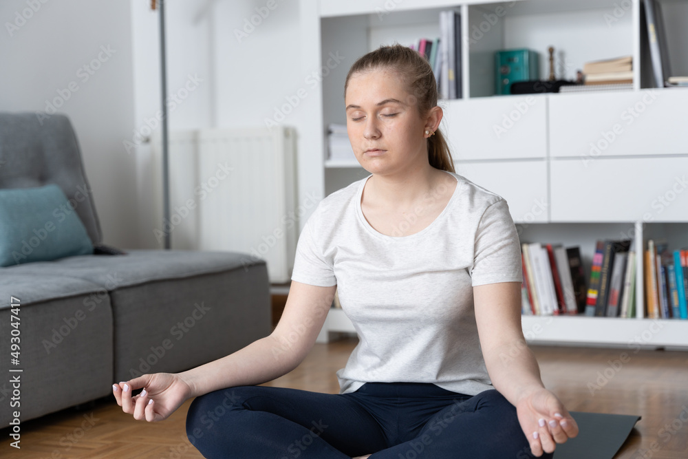 Female teenager meditating at home. Young woman making breathing exercise. Female teenager meditating at home. Young woman making breathing exercise.