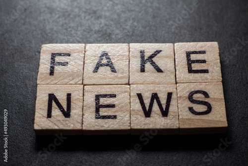 Macro of the words fake news formed by wooden blocks on black background photo