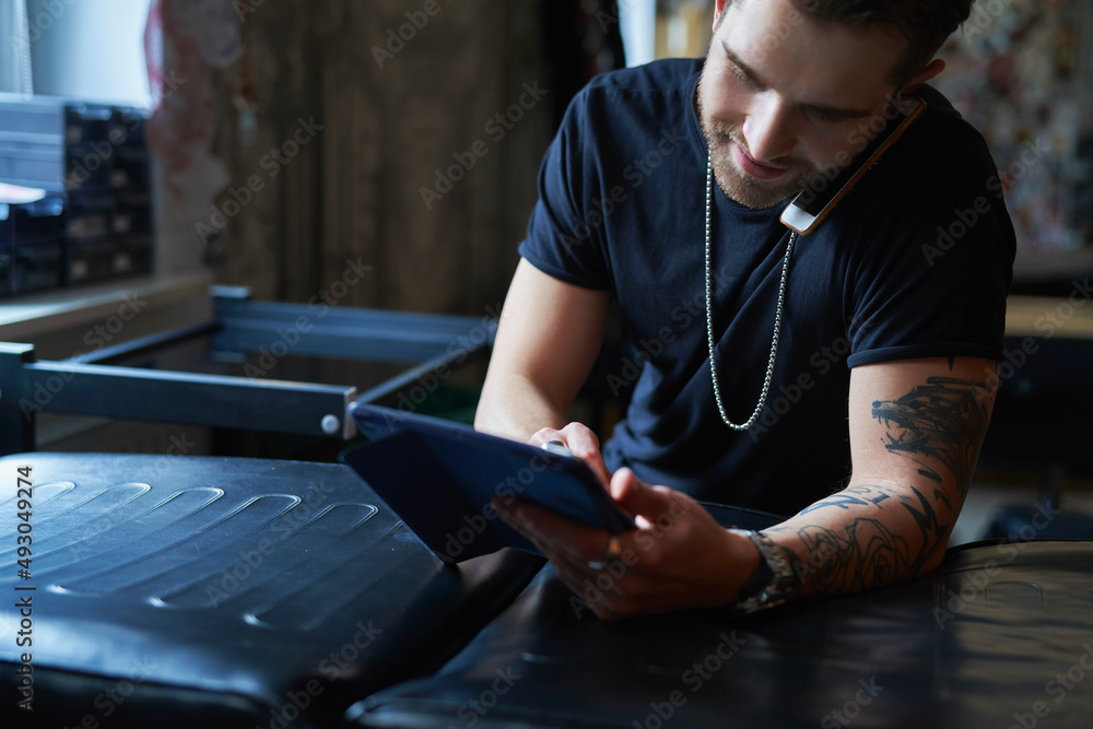 Caucasian tattoo artist talking by mobile phone and in tattoo studio Caucasian tattoo artist talking by mobile phone and in tattoo studio