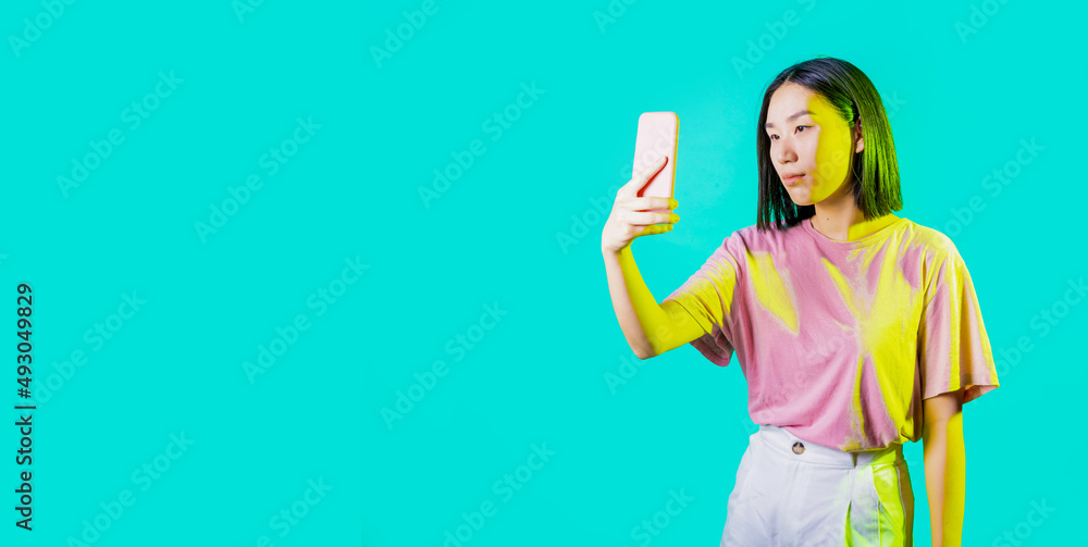 Young asiatic woman isolated using smartphone taking selfie Young asiatic woman isolated using smartphone taking selfie