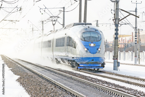 High-speed train rides at high speed in winter around the snowy landscape.