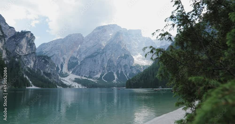 smooth ride from a steadicam through a bush to Lake Braies against the backdrop of rocky mountains and floating kayak boats on the water. overall plan smooth ride from a steadicam through a bush to Lake Braies against the backdrop of rocky mountains and floating kayak boats on the water. overall plan