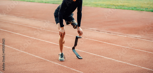 Tired runner with prosthetic leg standing on running track and taking a break. © dusanpetkovic1