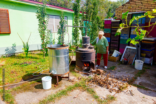 Cuadro en lienzo Woman is manually mixing fruit marc in distillation apparatus for making domesti
