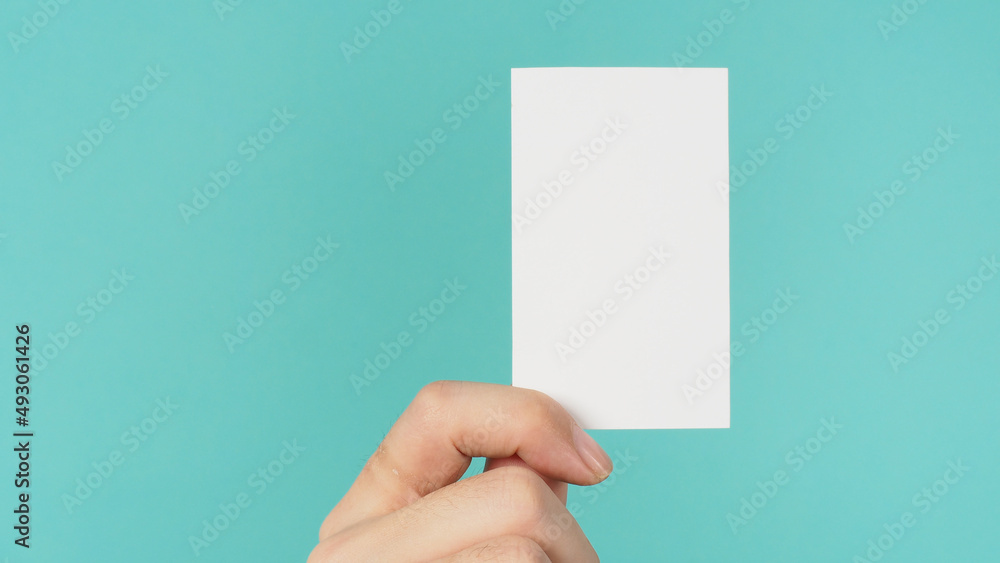 Empty space for text.Male hand holding white blank card isolated on mint green or Tiffany Blue background. Empty space for text.Male hand holding white blank card isolated on mint green or Tiffany Blue background.