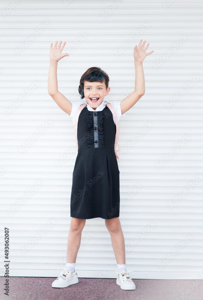 Vertical picture of 9 years old happy caucasian school girl on white background with hands up. Happy girl wants to learn. Smiling child in school uniform. Vertical picture of 9 years old happy caucasian school girl on white background with hands up. Happy girl wants to learn. Smiling child in school uniform.