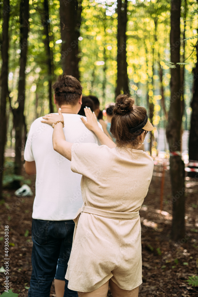 Team building exercise. People stand behind each other and hold their shoulders with their hands. Back view Team building exercise. People stand behind each other and hold their shoulders with their hands. Back view