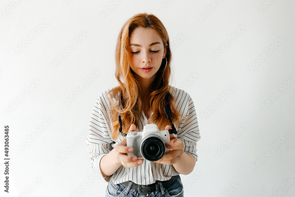 Fototapeta premium Young woman photographer looking at the live view on her modern camera, woman is enjoying the process