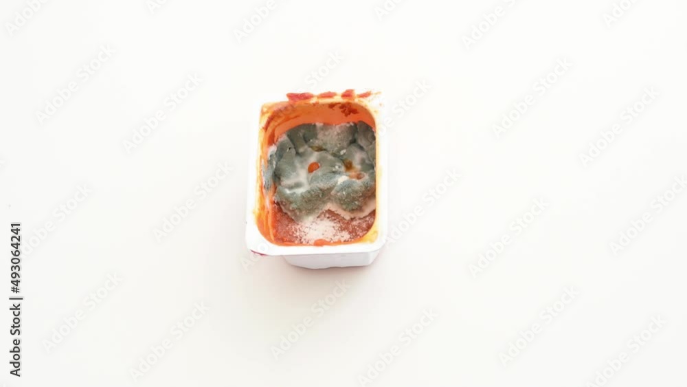 Mold on tomatoes sauce, spoiled rotten products. Food waste. Person's hand in gloves puts box with sauce, on white table. blue mold - mushroom on expired products. Mold on tomatoes sauce, spoiled rotten products. Food waste. Person's hand in gloves puts box with sauce, on white table. blue mold - mushroom on expired products.