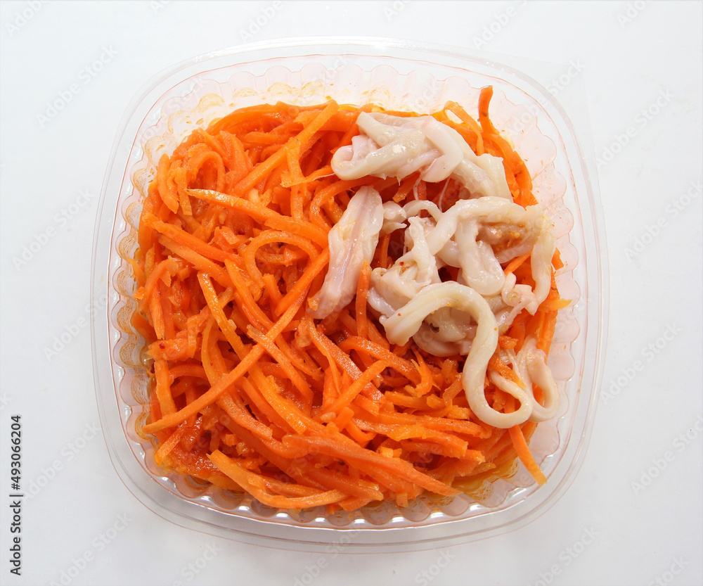 Carrot salad with squid in a plastic container. Lunch in a disposable dish. Carrot salad with squid in a plastic container. Lunch in a disposable dish.