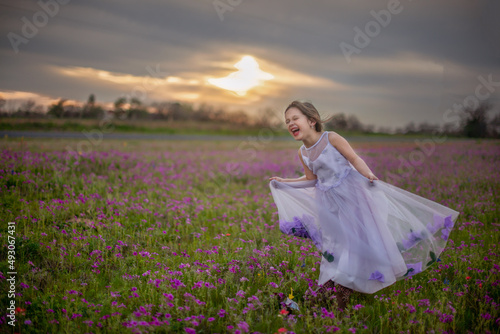 Little Girl Laughing In Texas Wildflower Field In Purple Dress