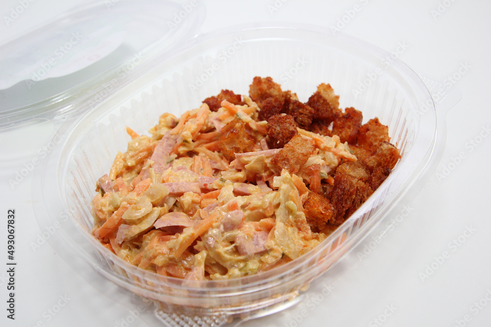 Salad Obzhorka in a plastic container. Lunch in a disposable dish.