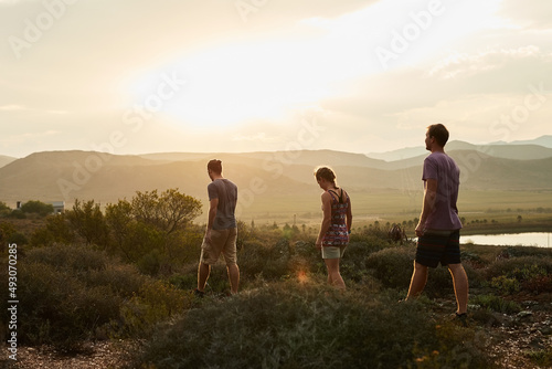 Life is better in hiking boots. Rearview shot of three young hikers on a mountain trail. photo