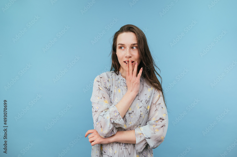 Gentle lady in a dress on a blue background looks away with a dreamy face. Isolated. Gentle lady in a dress on a blue background looks away with a dreamy face. Isolated.
